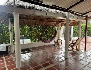 a porch with a hammock and chairs under a roof at Casa Cabaña Elena - Coveñas in San Antero