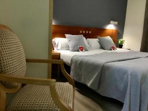 a hotel room with two beds and a chair at Hotel Paris Centro in Zaragoza