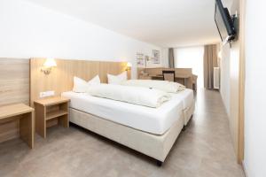 a bedroom with a large white bed and a table at Hotel Garni Brugger in Lindau