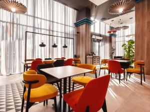 a restaurant with colorful chairs and tables and windows at ibis Tbilisi City in Tbilisi City