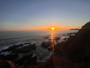 a sunset over the ocean with rocks in the water at MarLis in Quebrada Seca