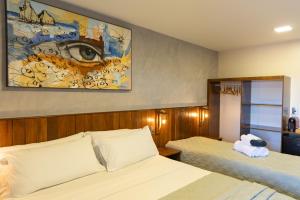 a bedroom with two beds and a painting of an eye at Pousada do Nica in Fernando de Noronha