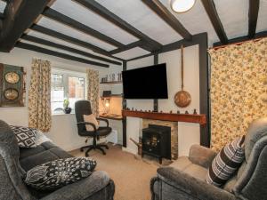 a living room with a fireplace and a flat screen tv at Cariad Cottage in Ludlow