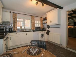 a kitchen with white cabinets and a wooden table at Cariad Cottage in Ludlow