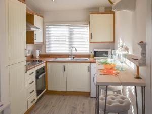 a kitchen with white cabinets and a counter with a table at Seaspace in Bacton