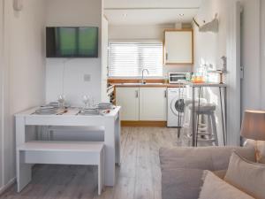 a living room with a white table and a kitchen at Seaspace in Bacton