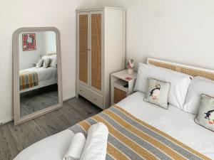 a white bedroom with a mirror and a bed at Seaspace in Bacton