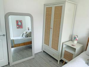 a white bedroom with a mirror and a bed at Seaspace in Bacton +14 photos