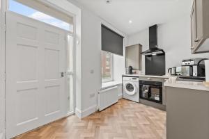 a kitchen with a white door and a washer and dryer at 1-Bed Duplex with Sofa Bed in Airdrie Lanarkshire - Long Stays - Free Parking in Airdrie +8 photos