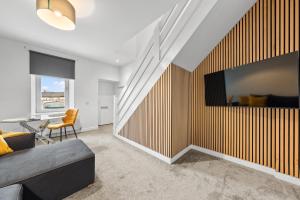 a living room with a couch and a tv on a wall at 1-Bed Duplex with Sofa Bed in Airdrie Lanarkshire - Long Stays - Free Parking in Airdrie