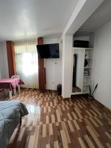 a room with a bed and a television and a wooden floor at Menacho's House in Caraz