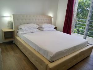 a bed with white sheets and pillows next to a window at Casa Alegiu in Las Galeras +91 photos