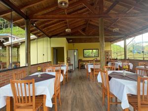 a dining room with white tables and wooden chairs at Pousada São Miguel Natureza e Descanso em Cunha SP in Cunha