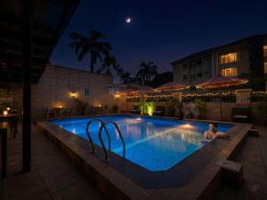 a man laying in a swimming pool at night at Bolton White Residence in Abuja