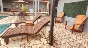 a patio with two wooden benches next to a pool at Chácara Com Piscina e Vista das Montanhas in Atibaia