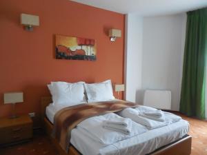 a bedroom with a large bed with orange walls at Villa AnnaLia - Rooms to Rent in Bacău
