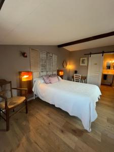 a bedroom with a large white bed and a chair at Chambres et Gîte Peyroutas "Amélie" à Vignonet St Emilion in Vignonet