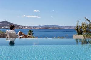 a man sitting in a chair next to a swimming pool at Paros Agnanti Resort & Spa in Parikia