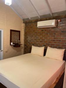 a bed in a room with a brick wall at Ayona Beach Villa in Katuneriya