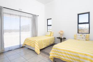 two beds in a room with a window at The North Atlantic Sands Beach House in Velddrif