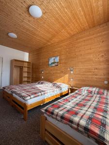 two beds in a room with a wooden ceiling at Penzion Emílie in Jeseník
