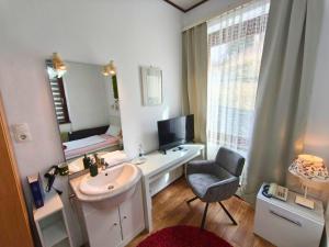 a bathroom with a sink and a mirror and a chair at Hotel Pfaff in Triberg +96 photos