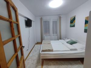 a white bedroom with a bed and a window at Apartament Abby in Sighişoara