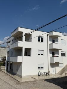 a white building with two chairs and a table at Apartmani Otium in Mostar