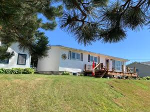 a white house with a porch and a yard at 101 Harborview Drive in North Rustico