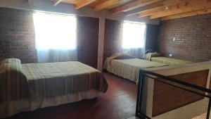 a bedroom with two beds and a brick wall at Dúplex para 4 San Luis in Barranca Colorada