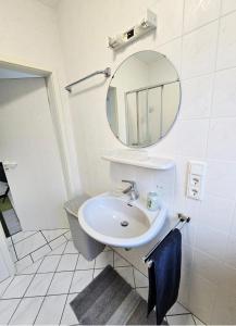 a white bathroom with a sink and a mirror at Apartment Kliniknähe in Idar-Oberstein