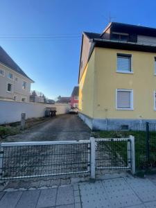 a yellow building with a fence next to a street at Gemütliche, lichtdurchflutete Wohnung in Karlsruhe