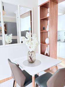 a white dining room table with chairs and a vase of flowers at Modern 3BR Apt with Pool within UN-Approved Zone, Kiambu Rd in Nairobi