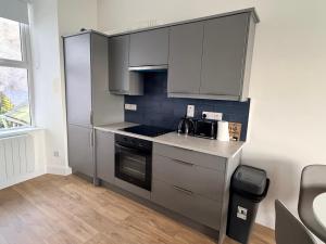 a kitchen with gray cabinets and a stove top oven at 2 Bed Apartment with Harbour Views Apt 2 in Cobh