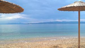 a beach with two umbrellas and the ocean at Dodis Village in Platanias