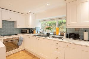 a white kitchen with a sink and a window at Tŷ Gwyn Bach, Conwy in Conwy