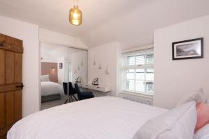a white bedroom with a bed and a desk at Tŷ Gwyn Bach, Conwy in Conwy