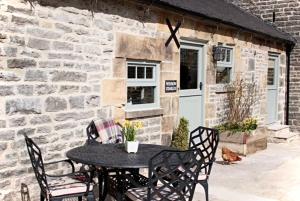 a black table and chairs in front of a brick building at Winnow Barns Holidays in Ashbourne