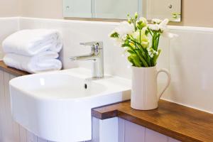 a bathroom with a sink and a vase of flowers at Winnow Barns Holidays in Ashbourne +23 photos