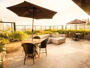 a patio with a table and chairs and an umbrella at Campos Sales by Xtay - Studios completos na região judiciária de Juvevê in Curitiba +23 photos