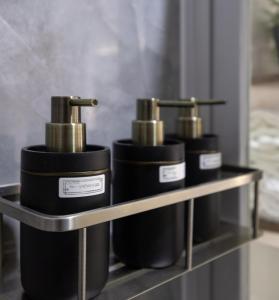 a shelf with four black and gold soap bottles at Cara Studio Mactan Cebu Cozy with Garden View at Primeworld District Tower H 103 in Lapu Lapu City