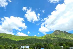 a blue sky with white clouds and green mountains at ELYMUS - Spacious 3-Bedroom Apartment With Private Rooftop and Balcony - Near Le Morne And Lagoon in La Gaulette