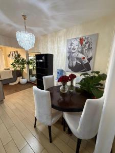 a dining room table with white chairs and a chandelier at Sweet Haven - Sports Rd in Westlands