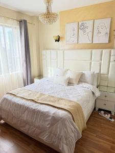 a bedroom with a large white bed and a chandelier at Sweet Haven - Sports Rd in Westlands