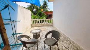 a patio with chairs and a table and an umbrella at 4 BHK villa with private Jacuzzi & Shared pool- Anjuna in Anjuna