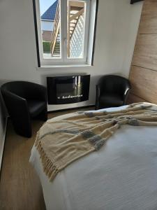 a bedroom with a bed and two chairs and a window at Studio Albert 1er in Oye-Plage