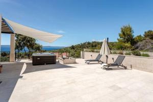 a patio with two chairs and a table and an umbrella at Sea View House with Jacuzzi - Casa Bianca Brač in Selca