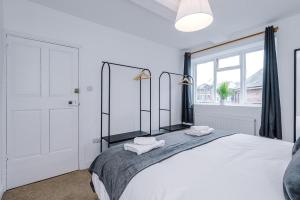 a white bedroom with a large bed with two towels at 15A Well Street in Ruthin