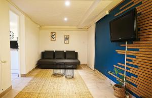 a living room with a couch and a tv on a wall at Cocoon Spa in Issenheim