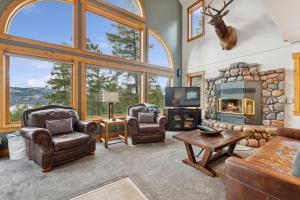 a living room with a fireplace and chairs and a tv at Elk Run in Whitefish